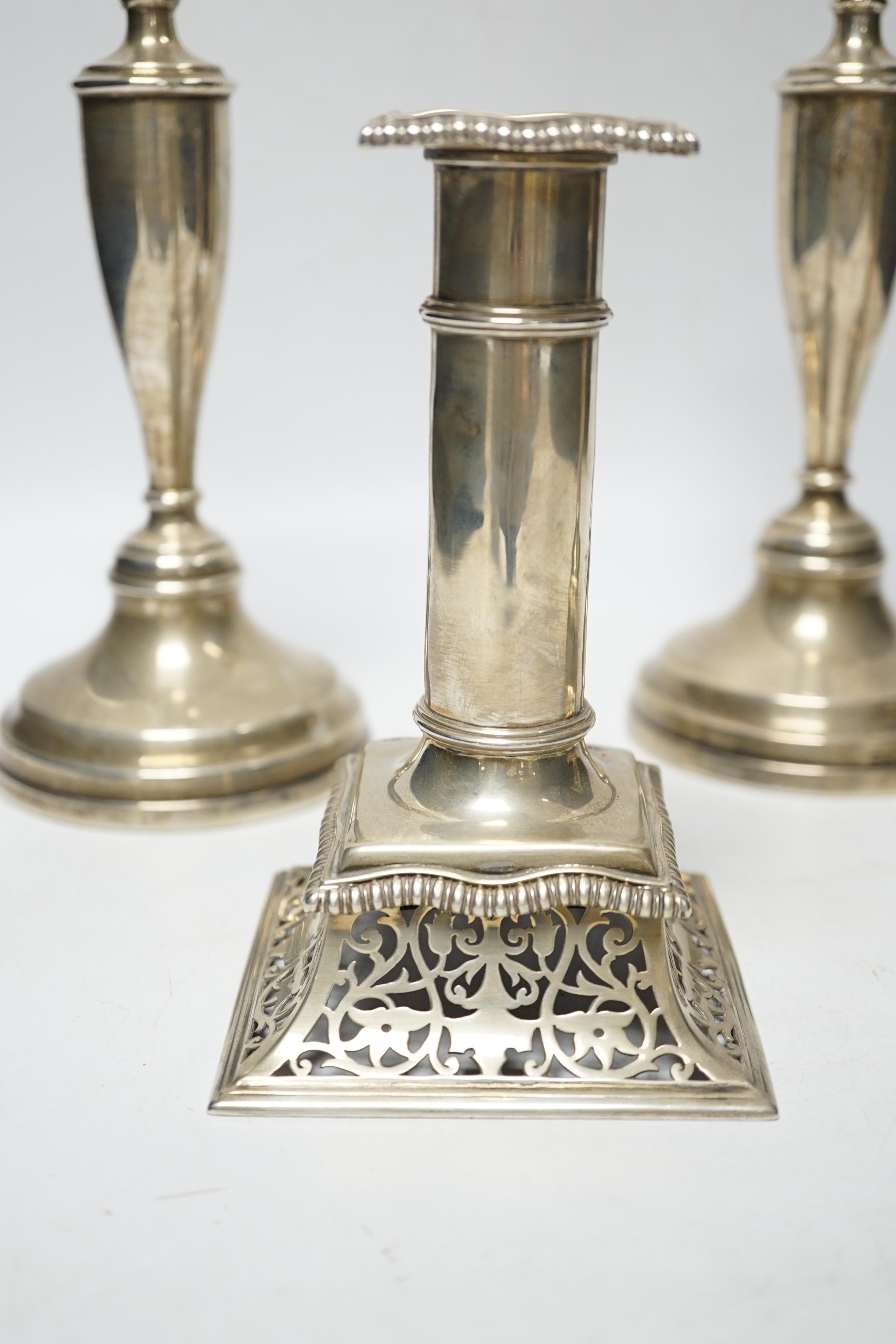 A pair of Victorian silver candlesticks, on pierced swept bases, William Leuchars, London, 1886, 15.2cm, weighted and a later taller pair of silver candlesticks.